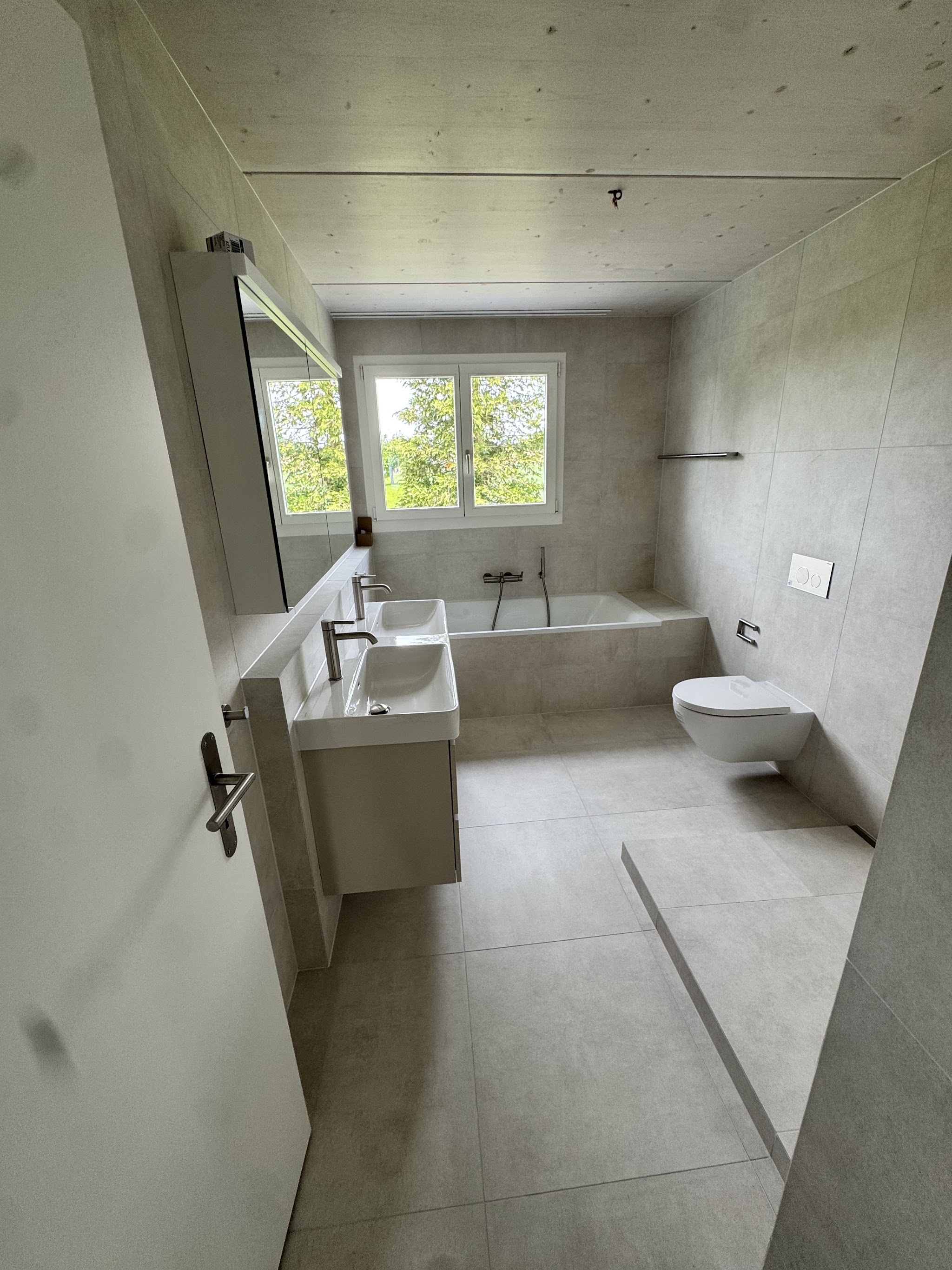 Renoviertes Badezimmer mit Badewanne und neuen Platten